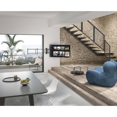 Moderne loft-appartement met bakstenen muren, trap, groot raam met uitzicht op de stad; tafel met kom en bank op de voorgrond.