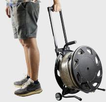 Een persoon in shorts en sportschoenen houdt een slangenwagen met een opgerolde slang vast.