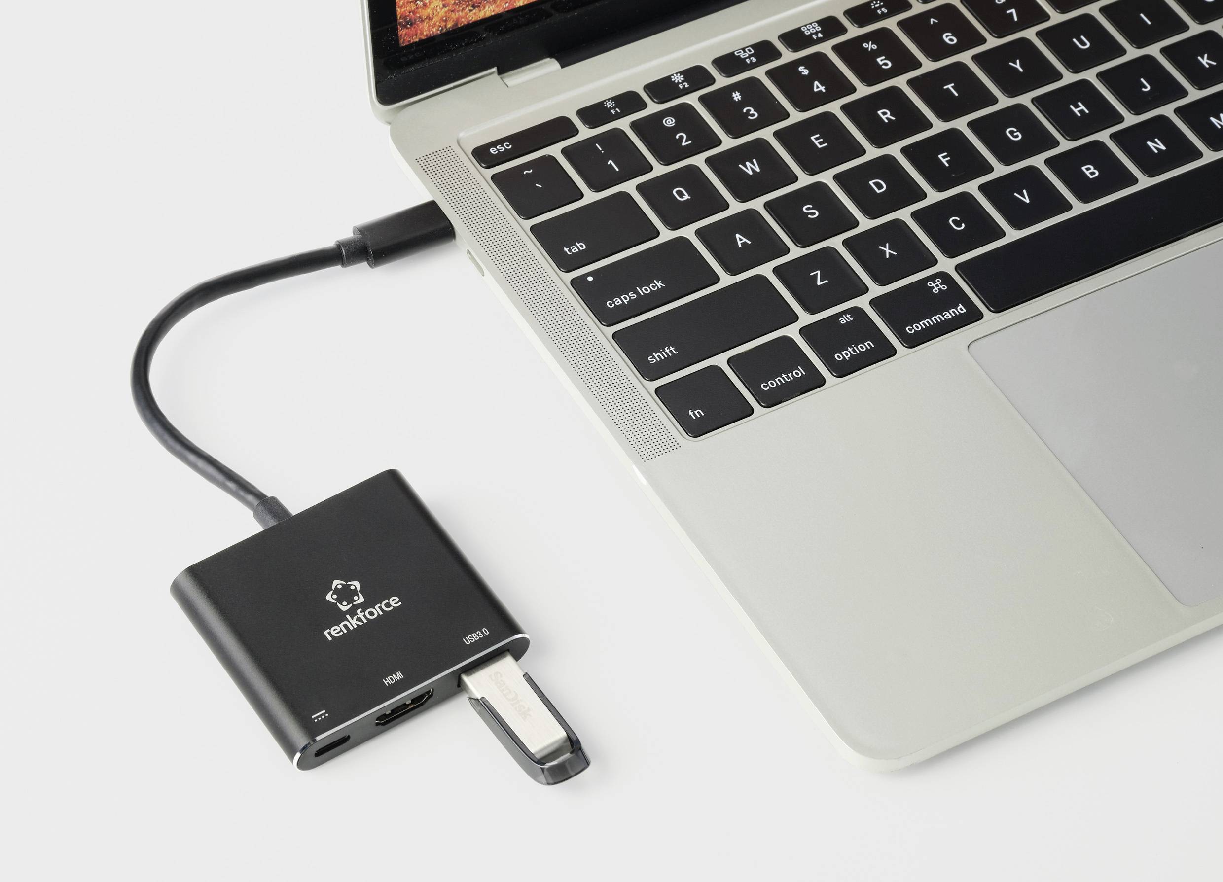 Een laptop is verbonden met een externe USB-C-hub die extra aansluitingen en een USB-stick uitbreidt.