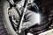 Onderaanzicht van een auto met verlichte inspectie, met focus op wielophanging en schokdempers. Mechanisch detail zichtbaar.