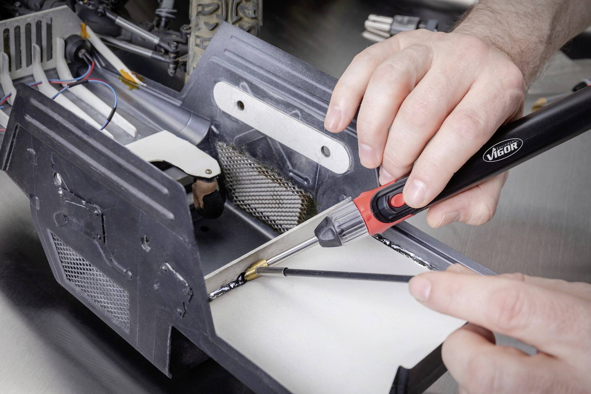 Een persoon soldeert met een soldeerbout aan een metalen voorziening, toont nauwkeurige handvaardigheid in een technische context.