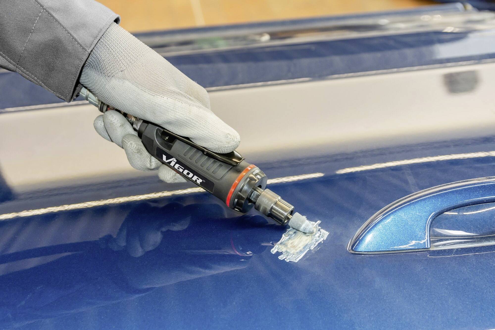 Een persoon gebruikt een handig reparatiegereedschap om krassen op de autolak te verwijderen.