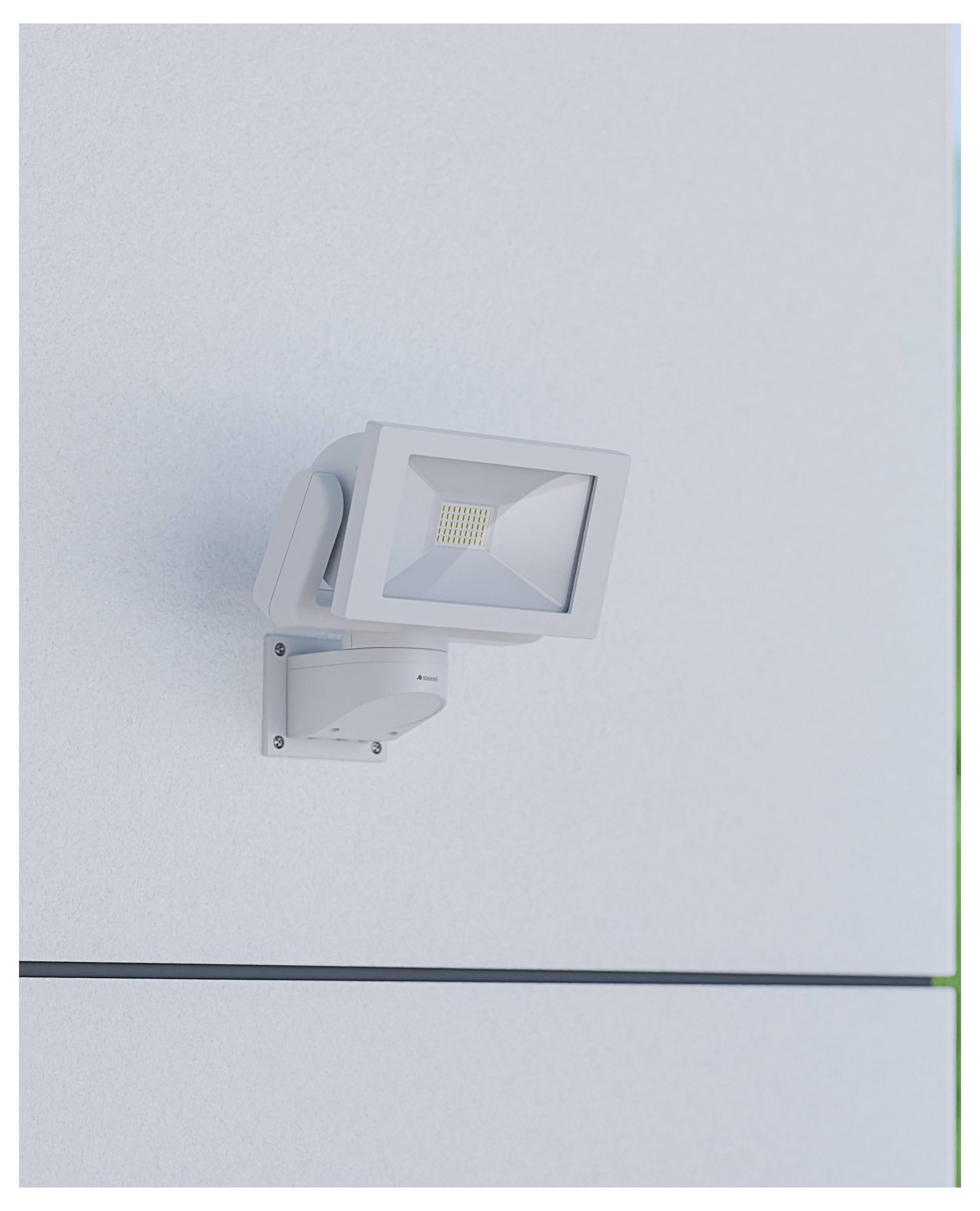 Wit LED-beveiligingsschijnwerper gemonteerd op een wandbeugel tegen een effen lichtgekleurd buitenmuur.