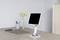 Een bureau met een tablet op een standaard, een laptop, een smartphone en een pennenhouder met plantendecoratie.