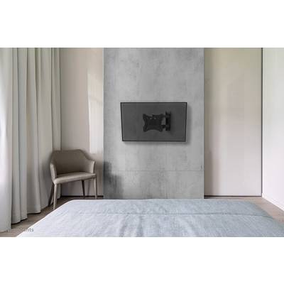 Een modern slaapkamer met een grijze fauteuil, een bed met een blauwe sprei en een tv die aan de muur is bevestigd.