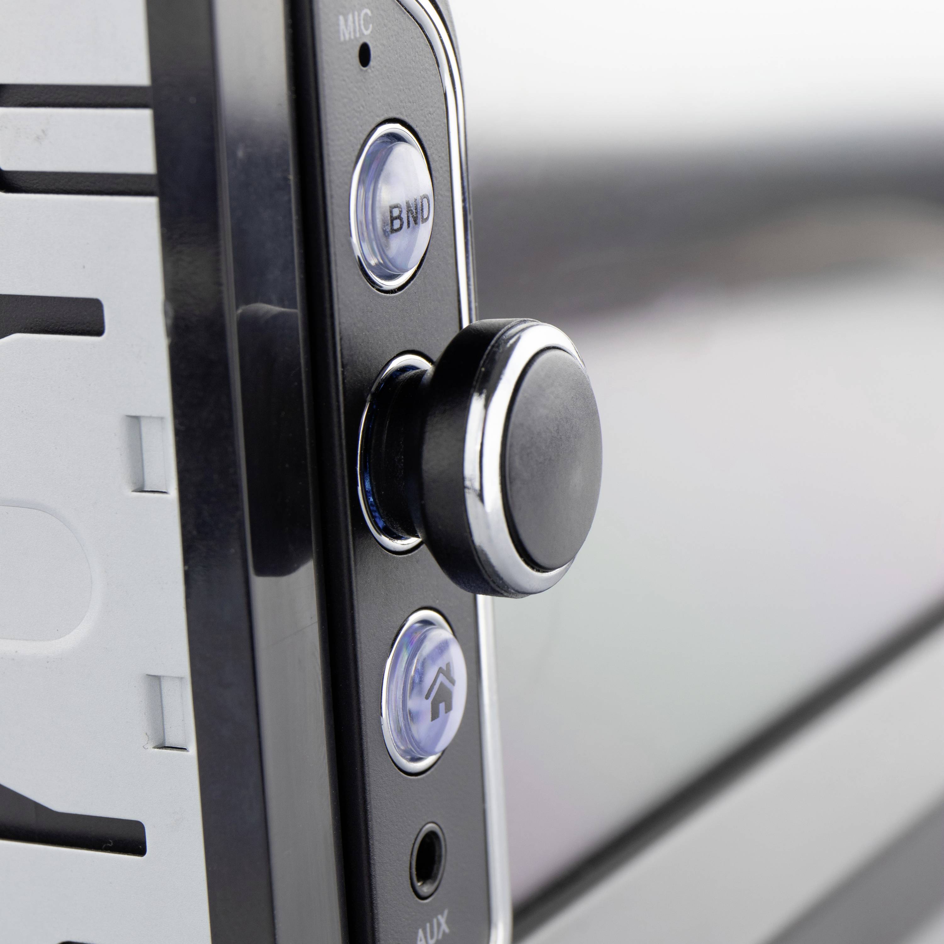 Close-up van een autoradio-bedieningspaneel met een draaiknop en drie knoppen. Eén knop is gemarkeerd met een microfoon-icoon.