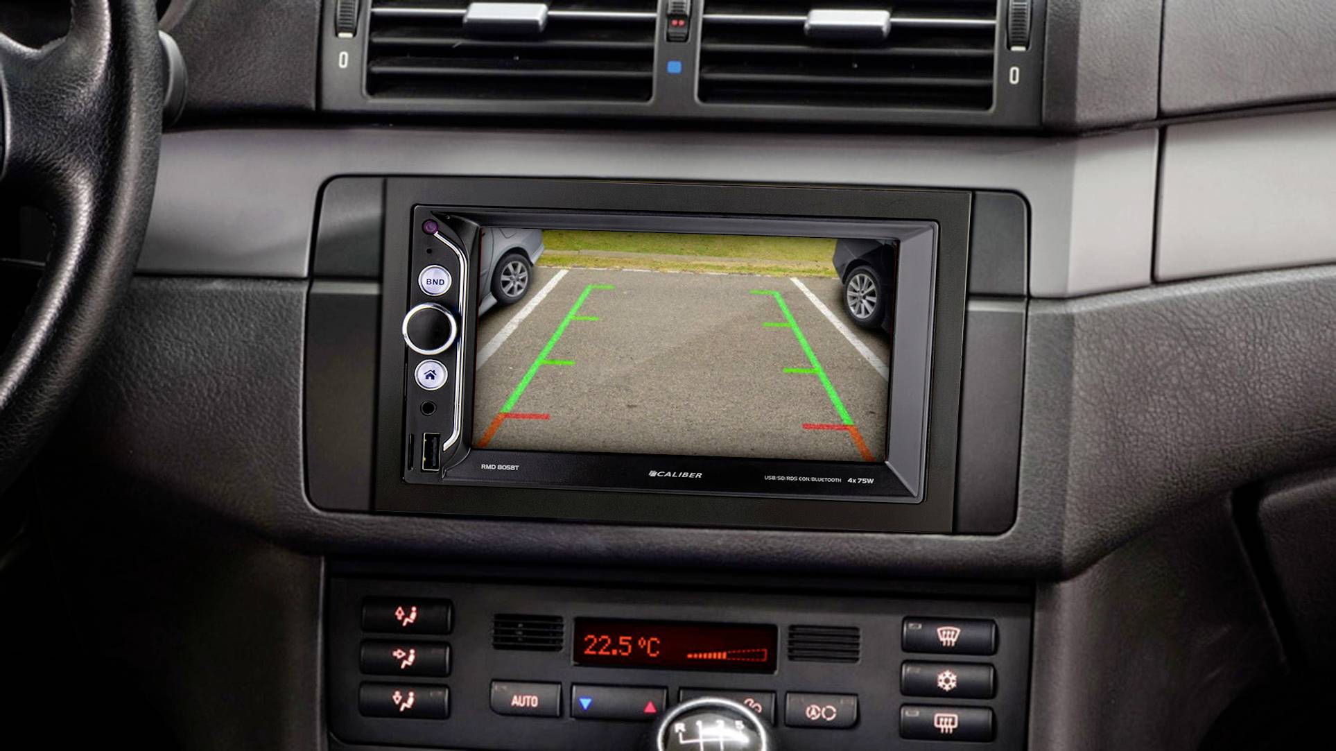 Achteruitrijcamera in auto toont parkeerplaats op scherm. Gekleurde lijnen helpen bij het uitlijnen. Schakelaars en knoppen omringen het scherm.