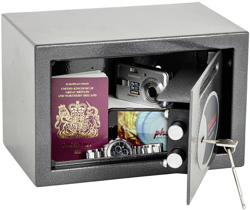 Een open kluis met een paspoort, een camera, een horloge en andere persoonlijke voorwerpen erin; de sleutel steekt in het slot.