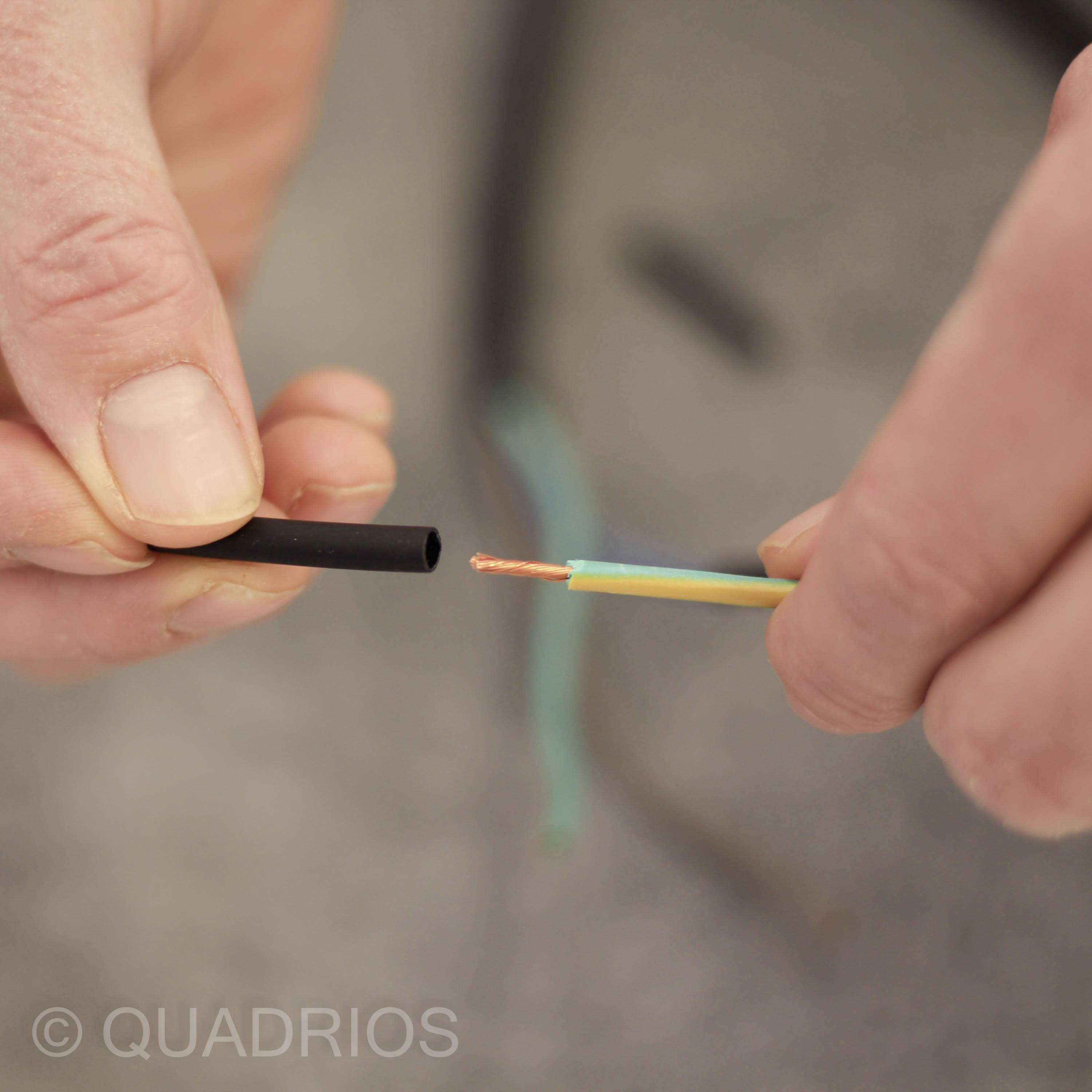 Een hand houdt een gestript kabel vast, waarbij de draadkern zichtbaar is; een andere hand houdt het kabelisolatiedeel vast.