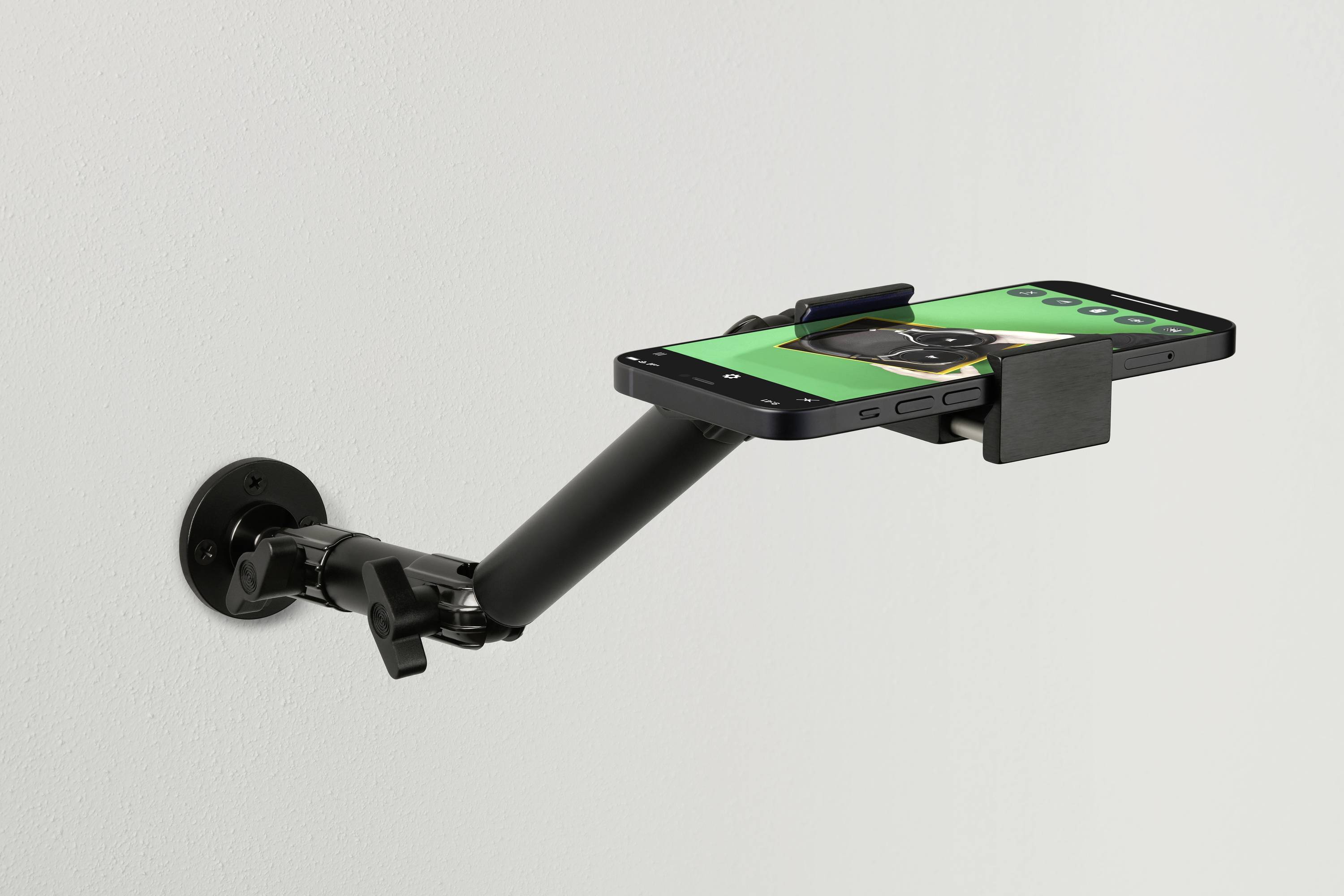 Een smartphone is gemonteerd in een houder aan de muur. Het scherm toont groene en zwarte kleuren met een gebruikersinterface.