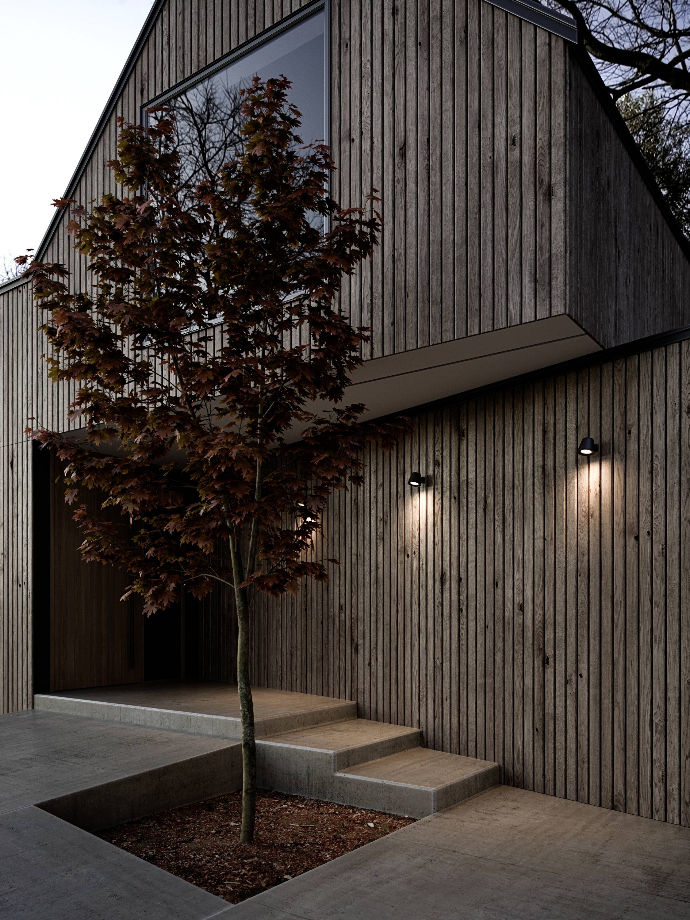 Modern houten huis met schuin dak; verlichte ingang, eenvoudige betonnen treden; boom op de voorgrond.