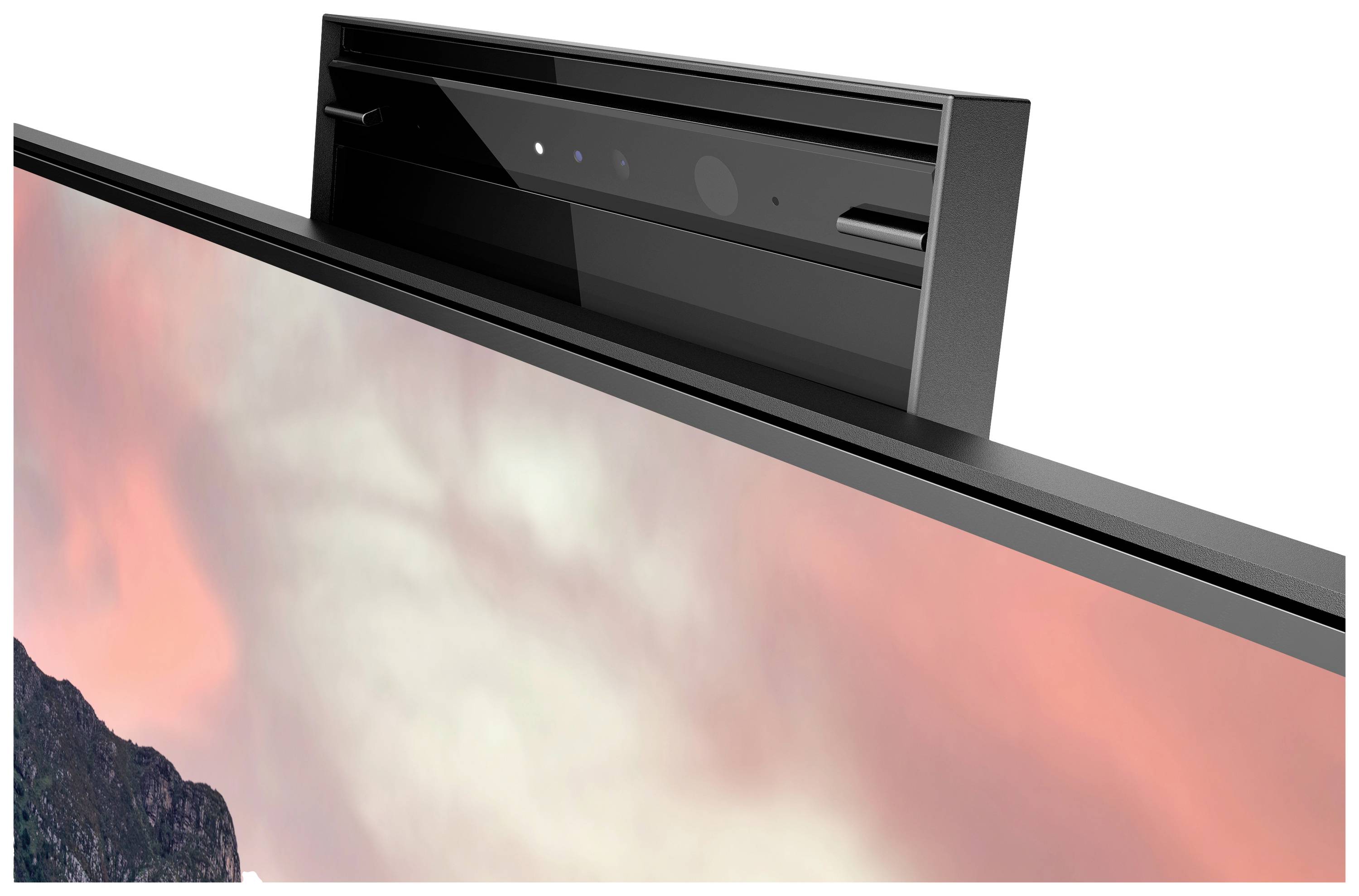 Een monitor met geïntegreerde webcam wordt getoond. Op de achtergrond is een onscherp landschapsbeeld te zien.