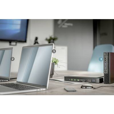 Een vergaderruimte met twee laptops op een tafel, verbonden met een dockingstation en een klein apparaat ernaast.