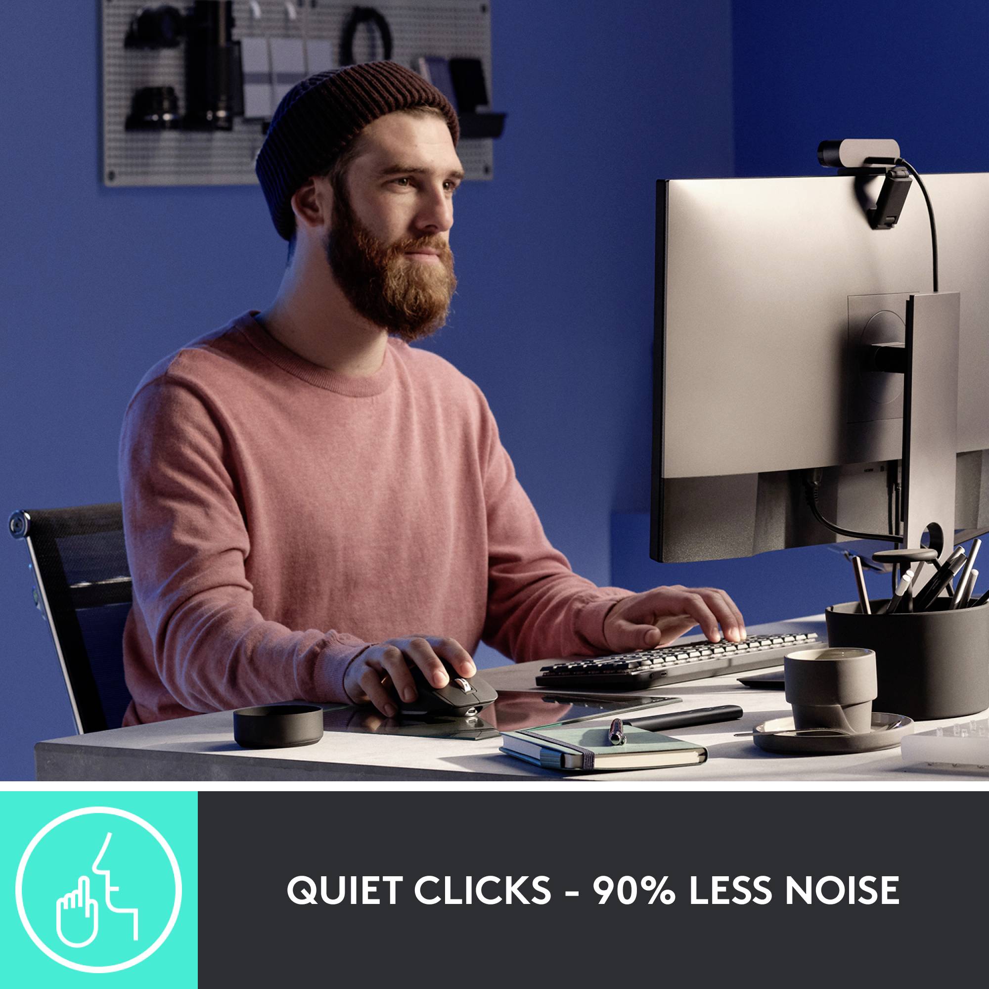 Een man werkt geconcentreerd aan een computer in een modern kantoor. Tekst: 'Zacht klikken – 90% minder geluid'.