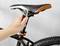 Hand past fietszadel aan met een moersleutel.