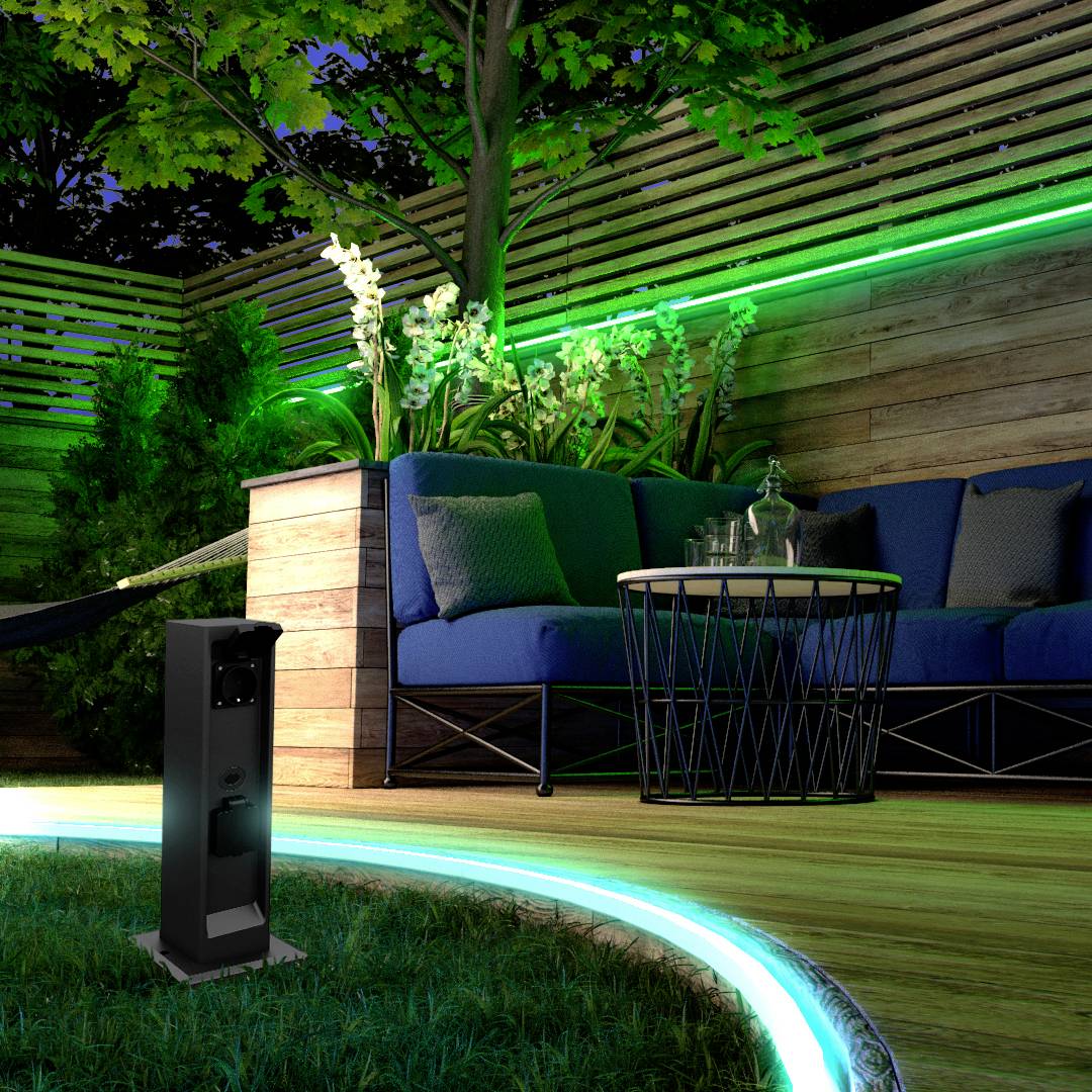 Avondopname van een moderne tuin met verlichte kantrandstenen, een blauwe bank, planten op de achtergrond en een staande lamp op de voorgrond.