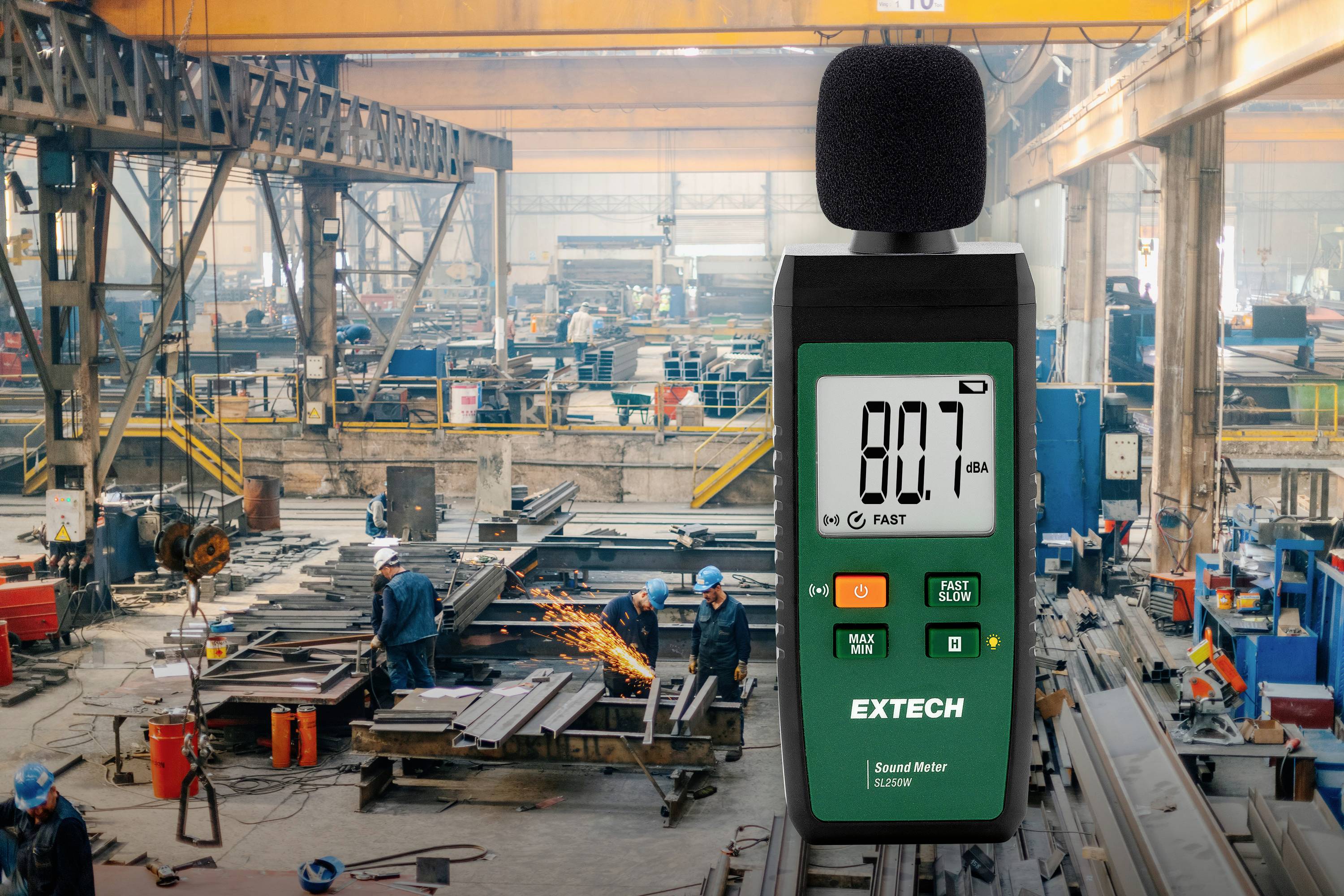 Een geluidsmeter geeft '80.7 dBA' aan in een lawaaierige fabriekromgeving. Arbeiders lassen en bewerken metaal.