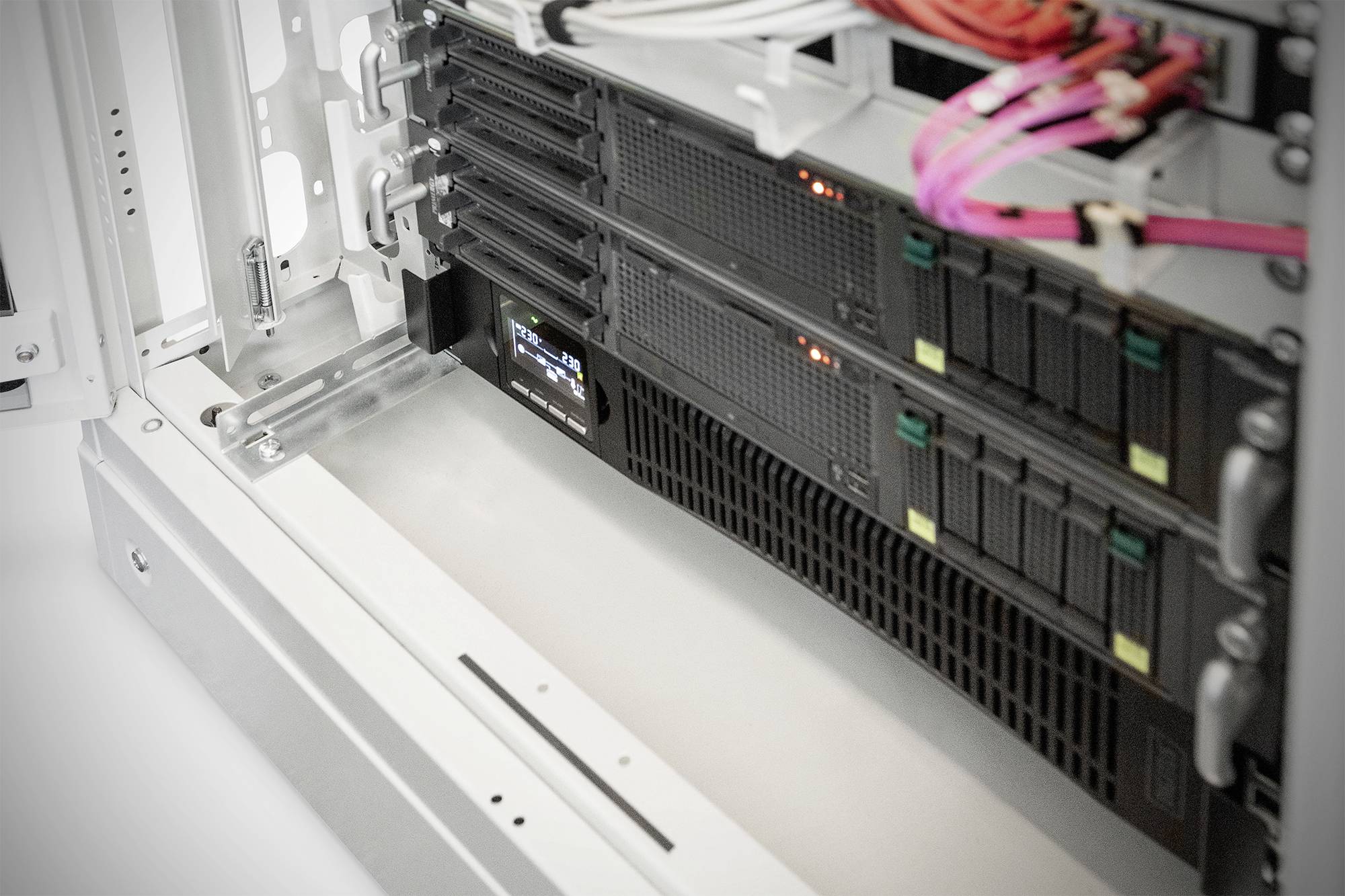 'Open serverrek met meerdere geïnstalleerde servers en oplichtende LED-indicatoren. Verschillende gekleurde kabels zijn aangesloten.'