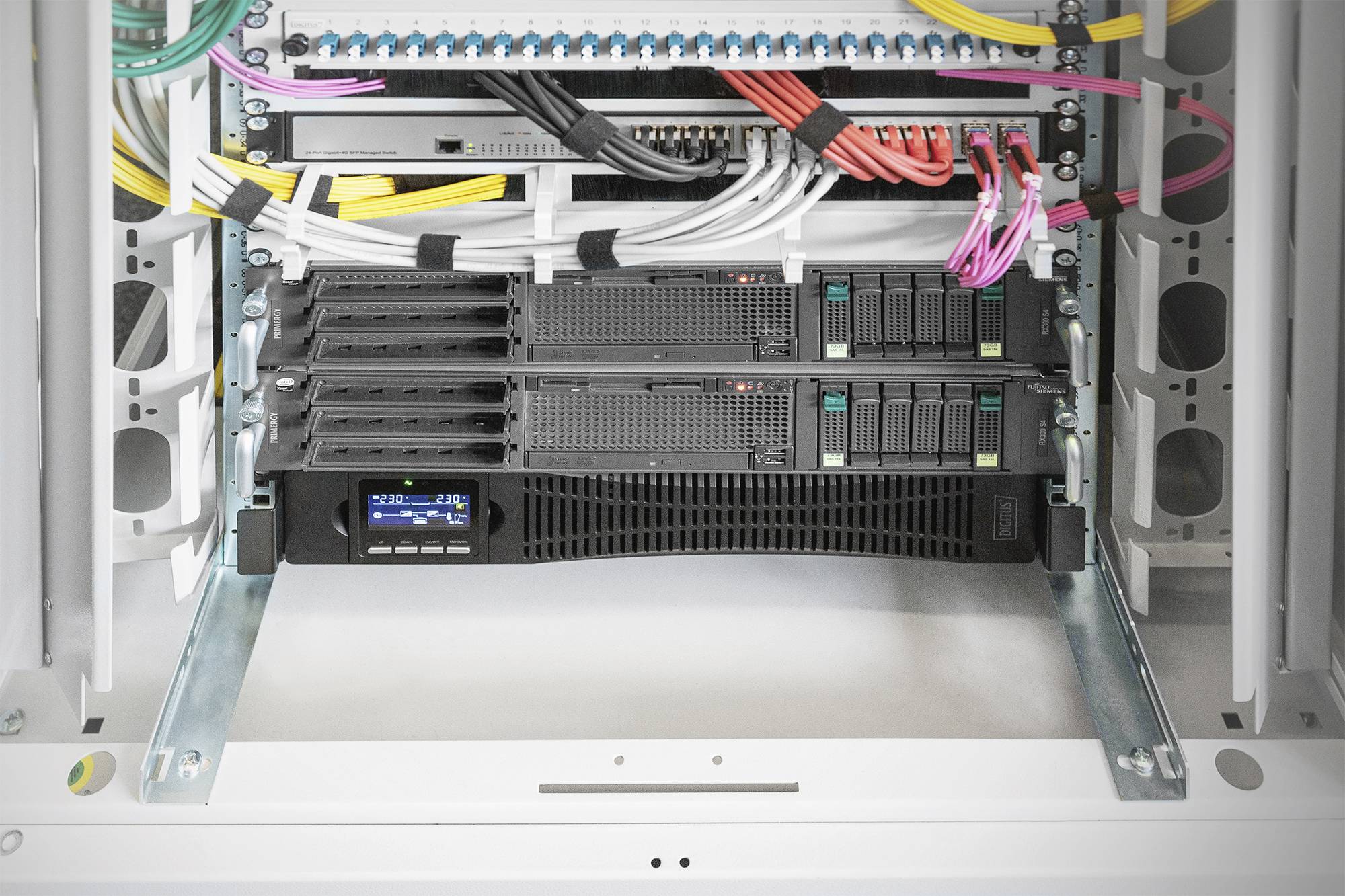 Een open serverrek met verschillende onderling verbonden kabels. Twee serverunits zijn gemonteerd, kabels zijn netjes georganiseerd.