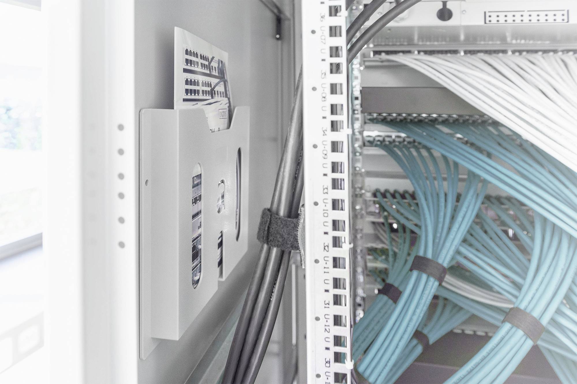 Een serverrek met blauwe netwerk- en zwarte stroomkabels. De bekabeling is netjes georganiseerd.
