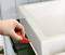 Hand die een rood gereedschap gebruikt om de siliconenkit rond een wastafel glad te strijken.