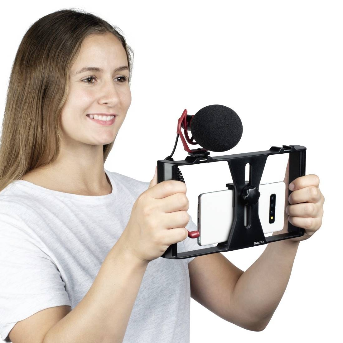 Een persoon houdt een smartphone-frame met microfoon vast, glimlacht en filmt.