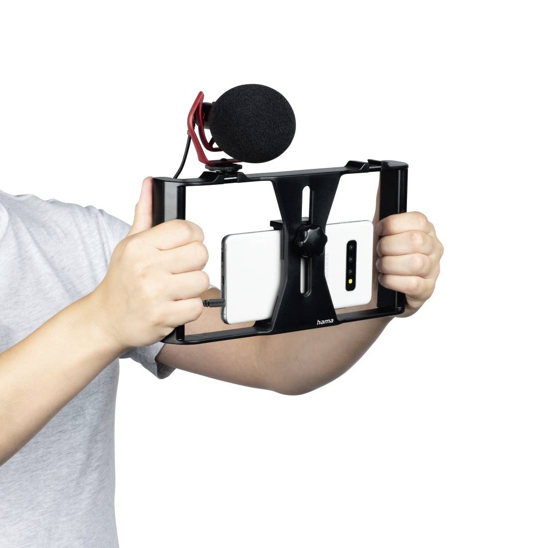 Een persoon houdt een smartphone vast in een stabiliserende houder met een microfoon, geschikt voor videoproducties of vlogs.
