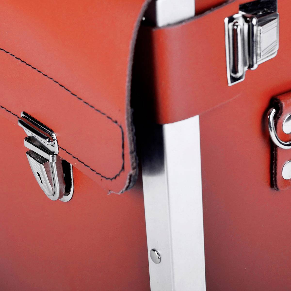 Close-up van een rode koffer met zilveren metalen gesp. De koffer oogt elegant en modern.