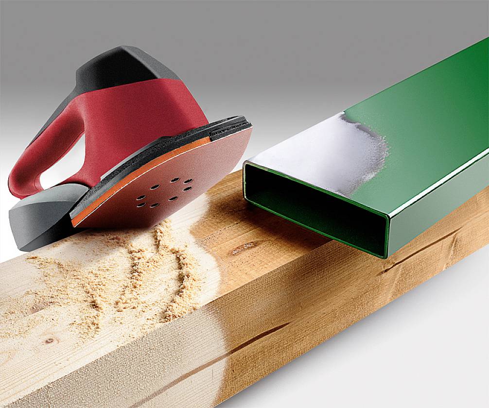 Slijpmachine bewerkt hout, ernaast een perfect geslepen groene metalen doos die het bewerkingsresultaat toont.
