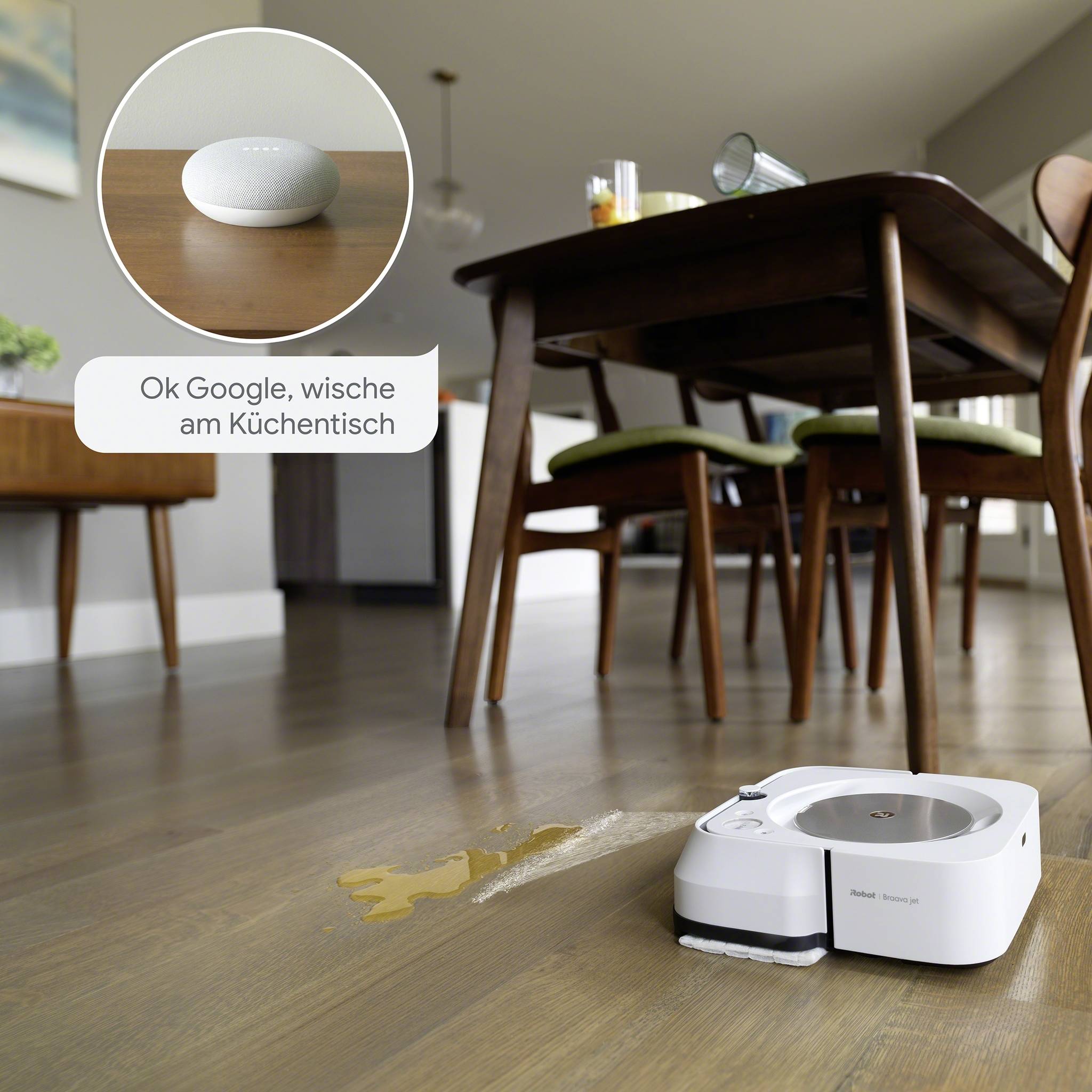 Een robotstofzuiger ruimt een gemorste vloeistof op een houten vloer op, terwijl een Google Nest een commando ontvangt: 'Oké Google, veeg de keukentafel schoon'.