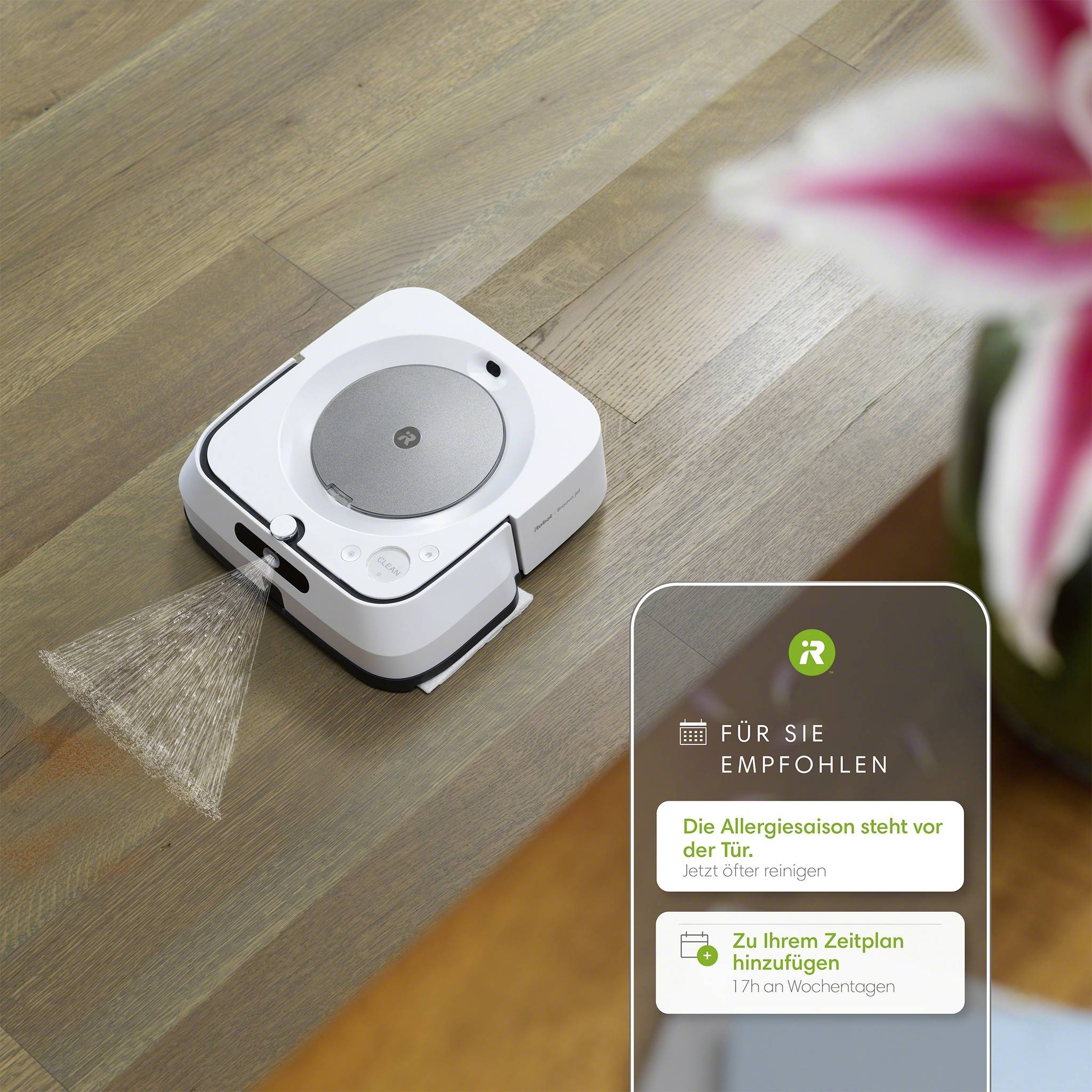 Een kleine, witte robotmop reinigt een houten vloer. Een plant is vaag zichtbaar op de voorgrond. Een digitaal informatievenster toont reinigingsaanbevelingen.