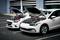 Twee auto's met geopende motorkappen staan naast elkaar geparkeerd. Startkabels verbinden de batterijen van beide voertuigen.