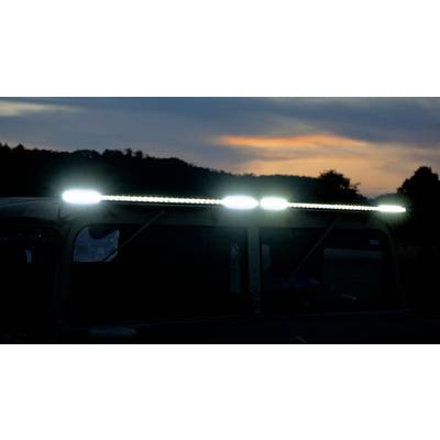 Een voertuigdak met oplichtende LED-verlichting bij schemering voor een met bomen bedekte horizon.