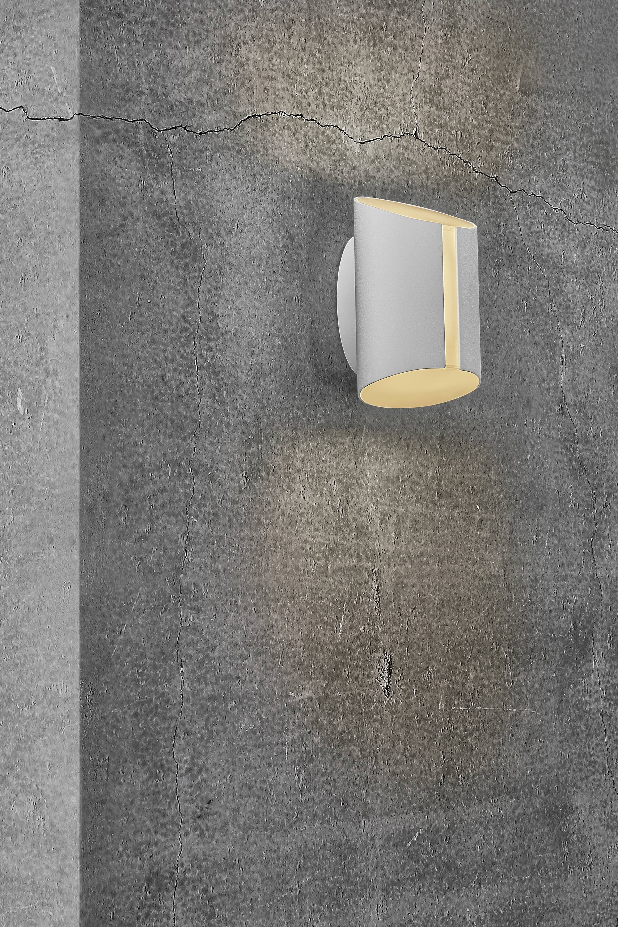 Wandlamp aan een grijze, gestructureerde betonnen muur die warm licht uitstraalt. Achtergrond toont scheuren in het beton.