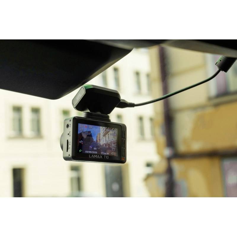 Een autocamera in het dashboard toont verkeersscènes op zijn scherm. De camera is gemonteerd aan de voorruit en aangesloten met kabels.