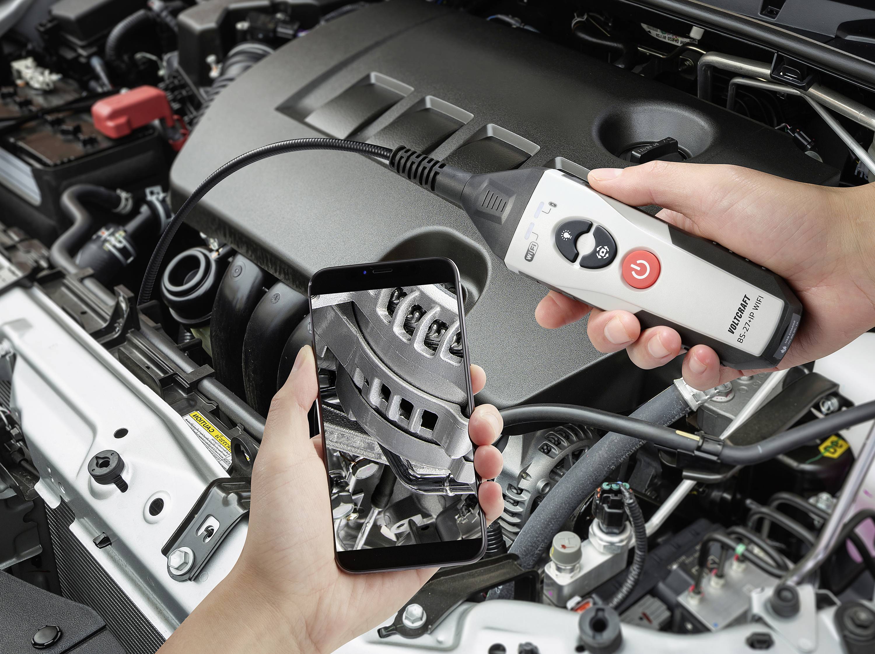 Een persoon inspecteert een automotor met een smartphone en endoscoop. Het display toont een close-upafbeelding van de motoronderdelen van binnenuit.