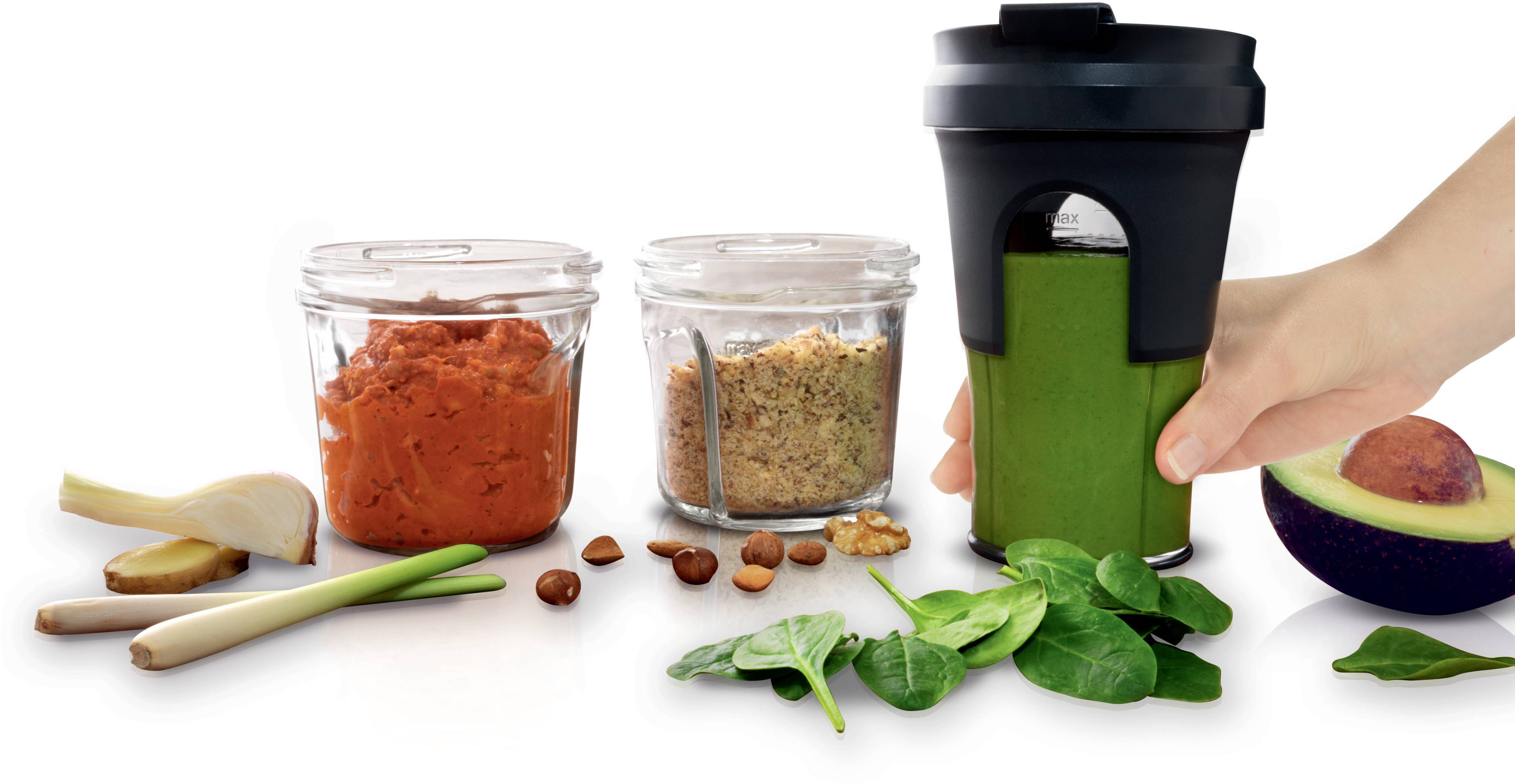Groene smoothie-ingrediënten met blender: Spinazie, gember, citroengras, amandelen, avocado en wortel- en dadelpasta. Hand houdt blender vast.