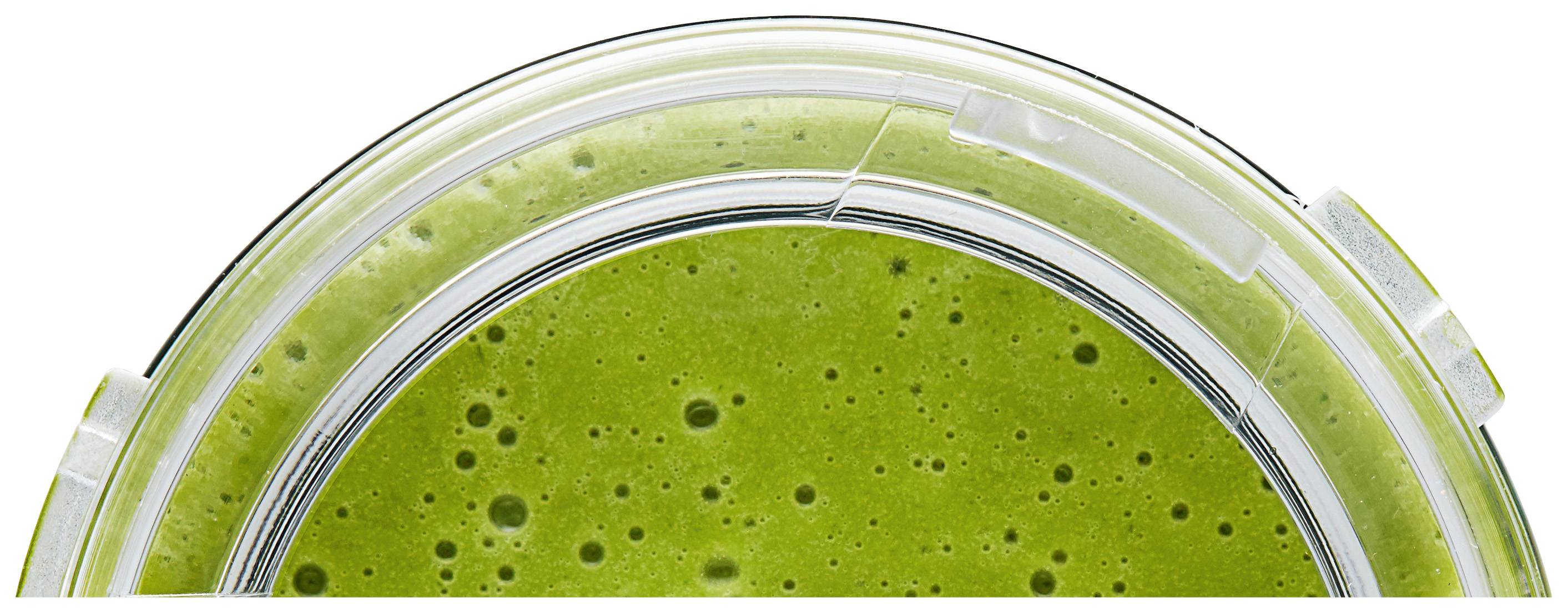 Groene smoothie gezien van bovenaf in een doorzichtige beker, textuur met luchtbellen zichtbaar.