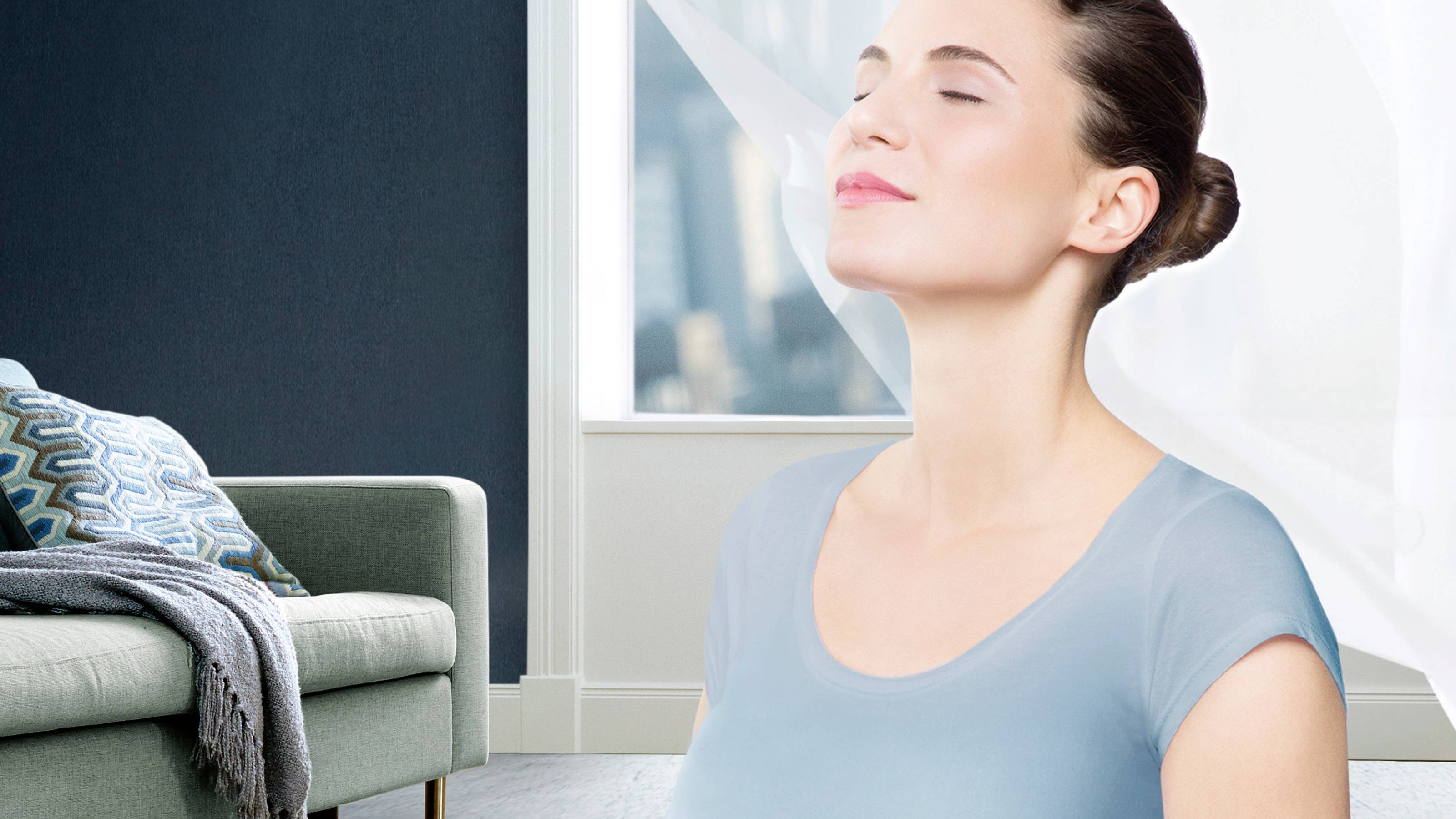 Een glimlachende persoon staat voor een open raam, waarlangs frisse lucht binnenstroomt. Het geeft een gevoel van ontspanning en frisheid.