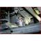 Een close-up van een auto-onderdeel met een waarschijnlijk reparerende handschoen. Metaalstructuren en mechaniek zijn zichtbaar.