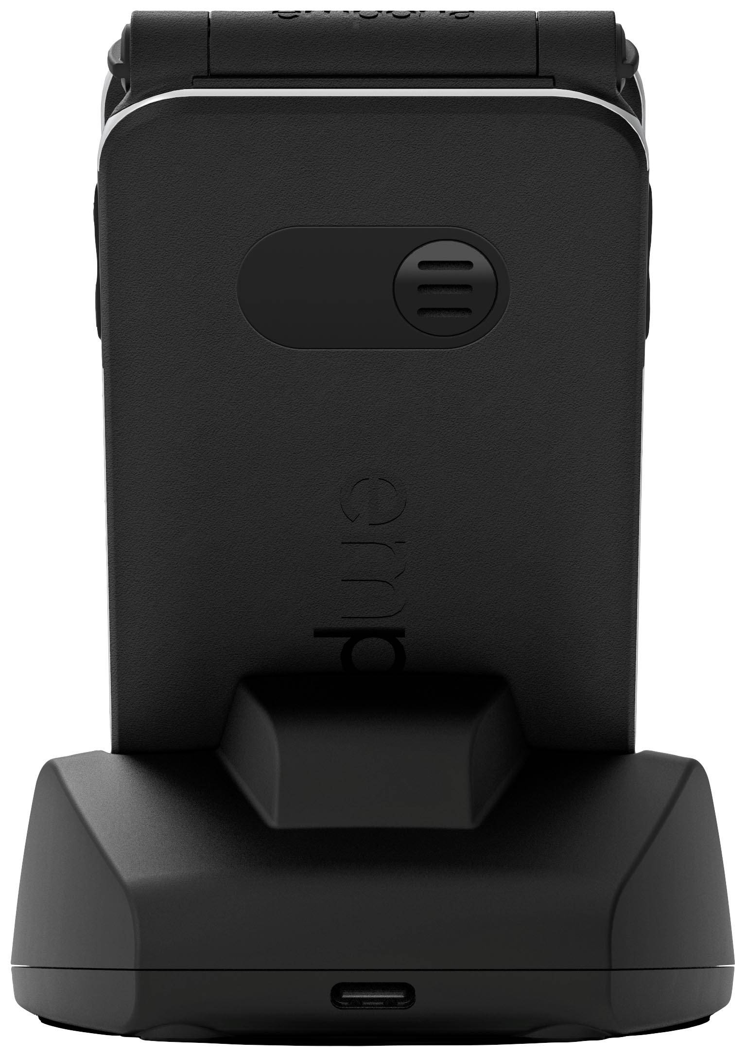 Een zwarte mobiele telefoon met grote toetsen staat op een laadstation. Het ontwerp oogt ergonomisch en is gericht op eenvoudige bediening.