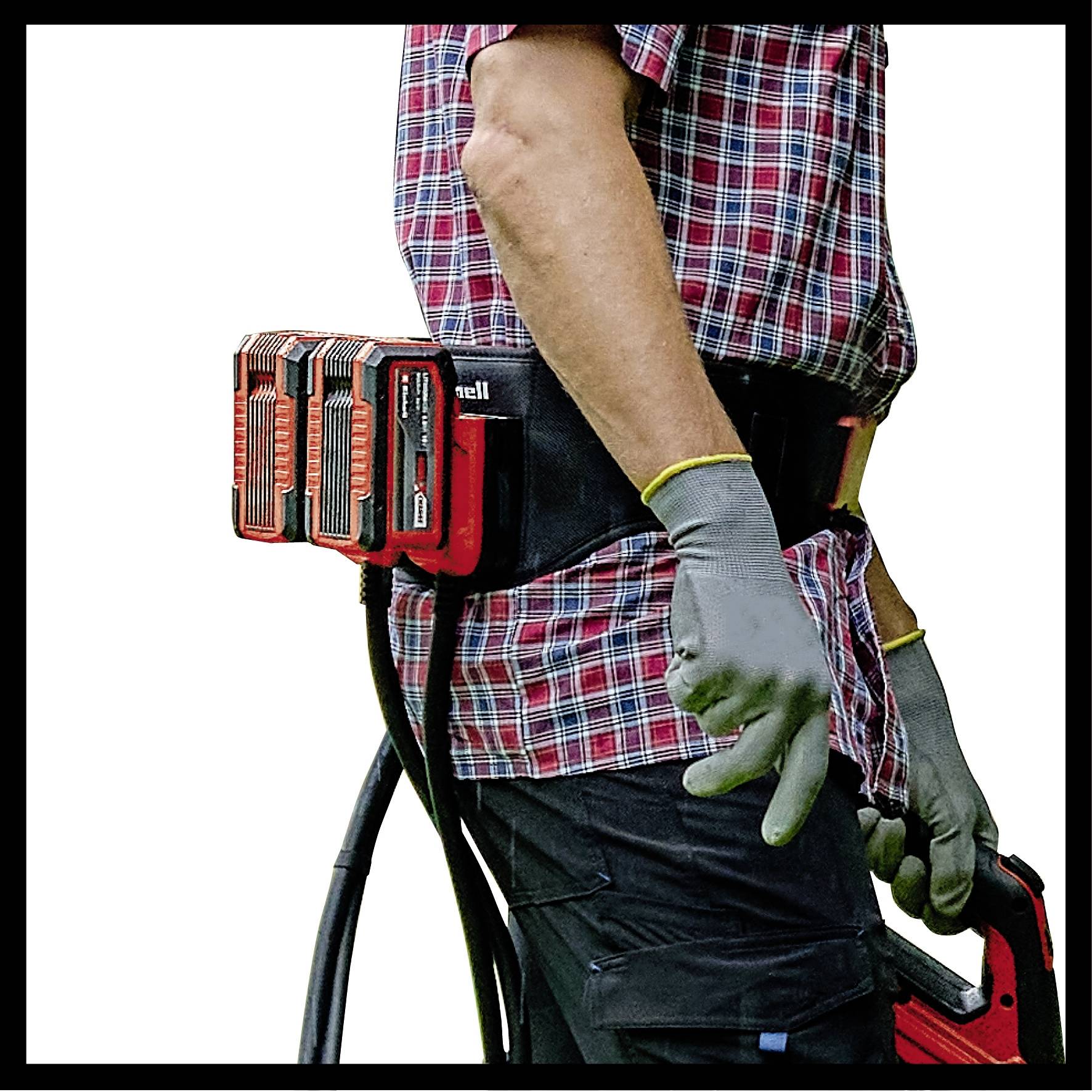 Een persoon in een geruit shirt en handschoenen werkt met een elektrisch gereedschap. Aan zijn riem bevindt zich een accupack.