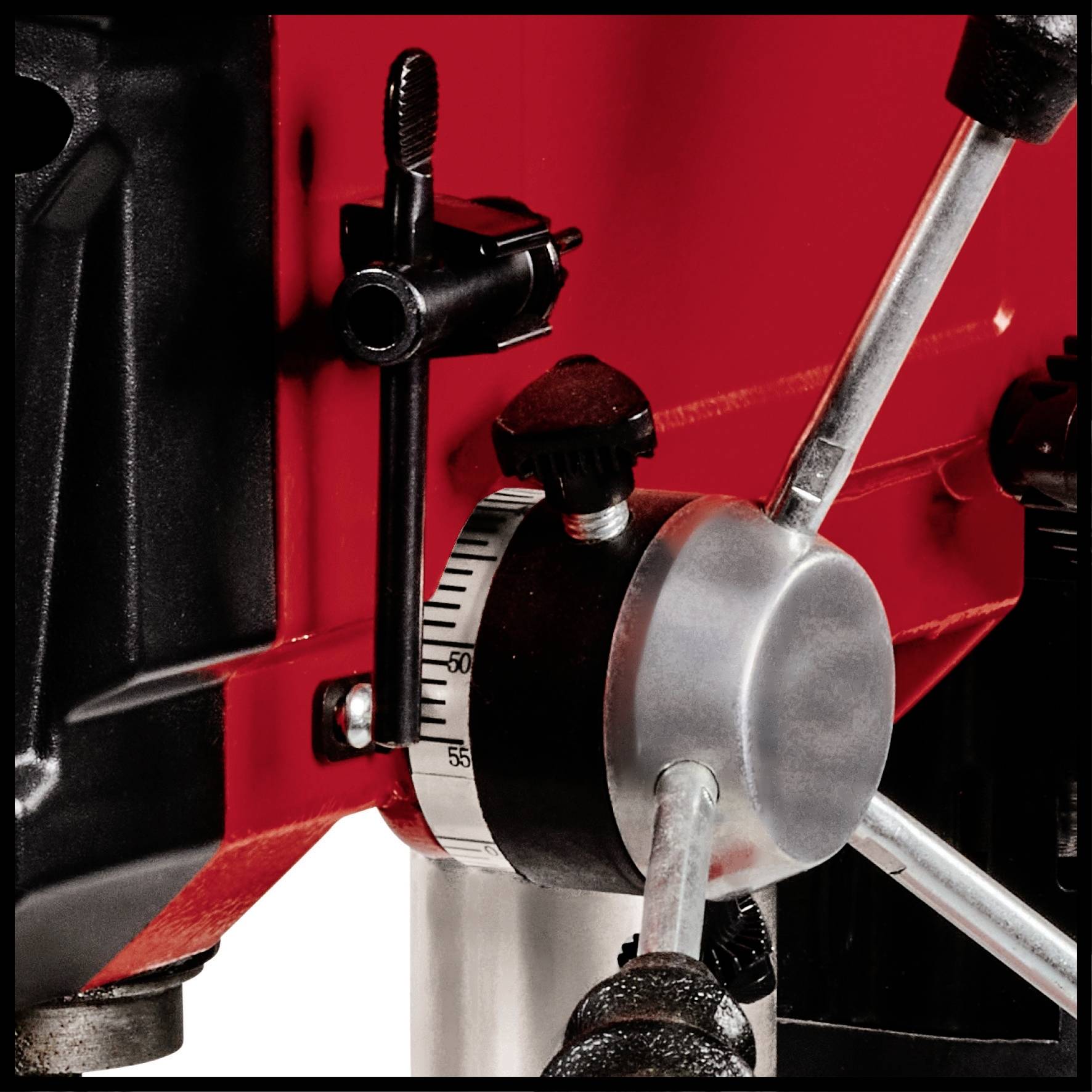 Een rood boormachine-onderdeel met een verstelbare hendel en een schaal voor het controleren van de nauwkeurigheid bij het boren.