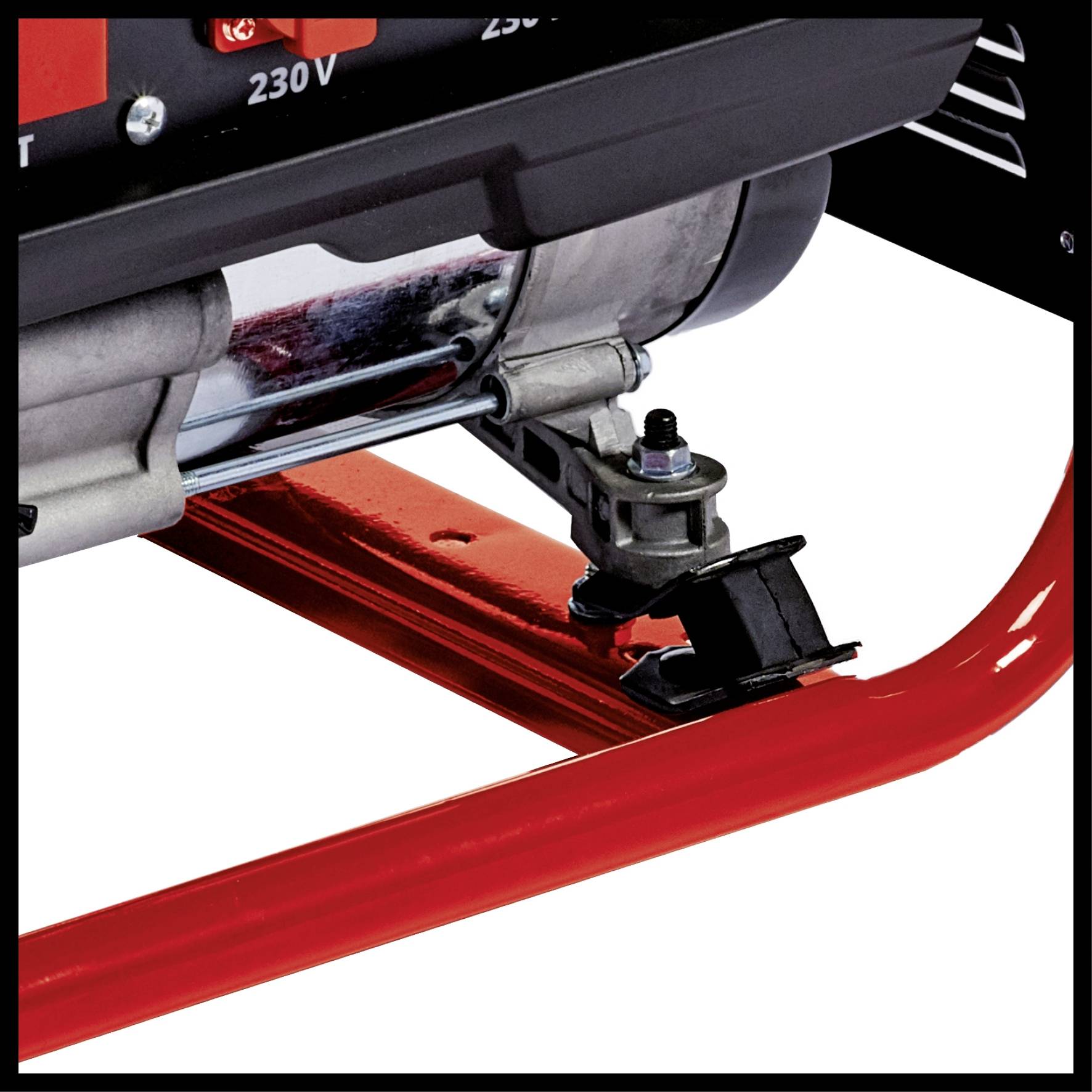 Een deel van een generator van metaal, gemonteerd op een rood frame. Een arm met een zwart mechanisme is zichtbaar.