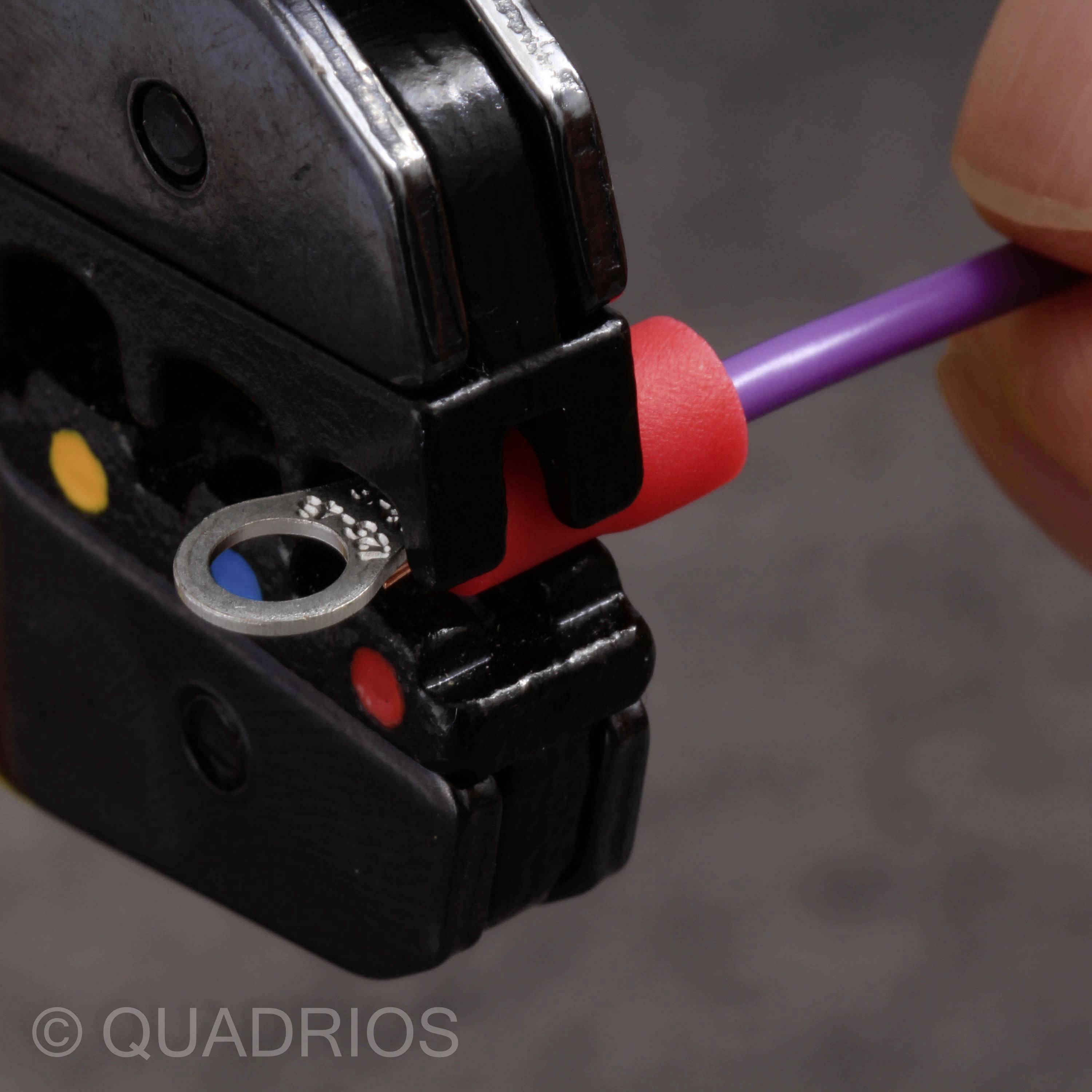 Een gereedschap perst een draad met een rode ring. Een hand houdt de draad vast. Rechts zijn gekleurde markeringen zichtbaar.