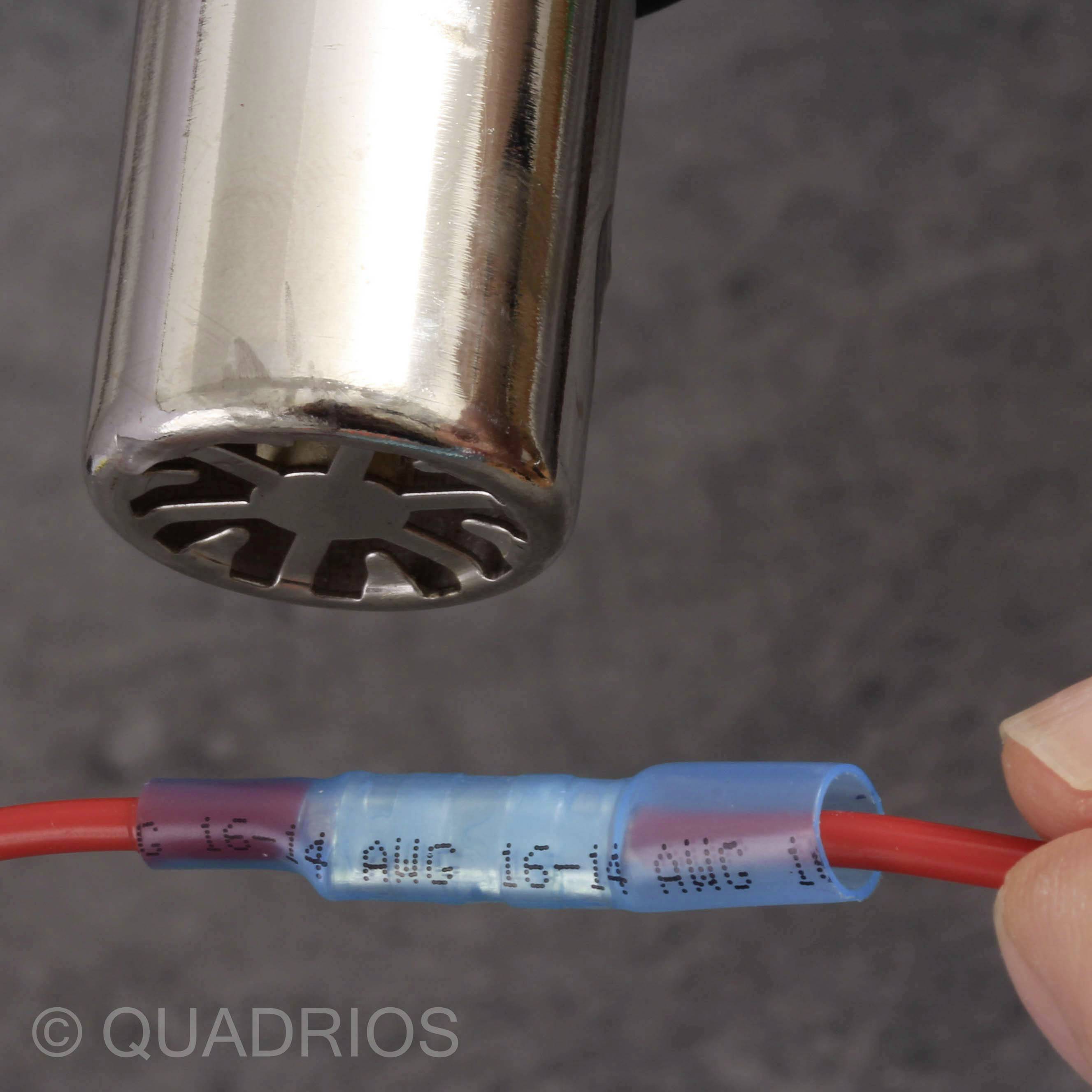 Een hand houdt een rood kabel vast met een blauwe aansluitbus. Op de achtergrond is een metalen voorwerp zichtbaar.