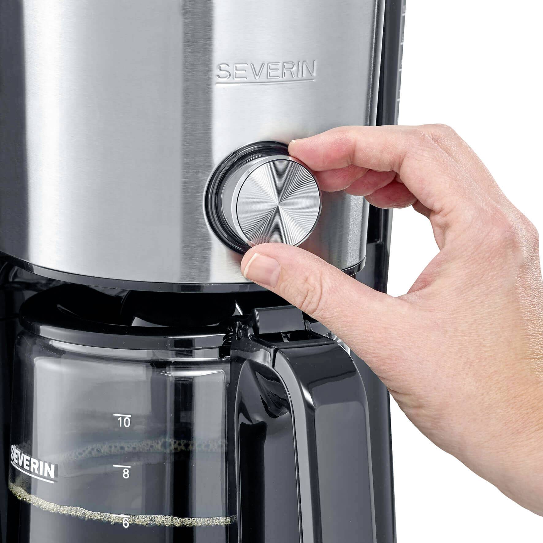 Een hand draait aan de knop van een zilveren koffiemachine. De kan toont een schaal voor de hoeveelheid.