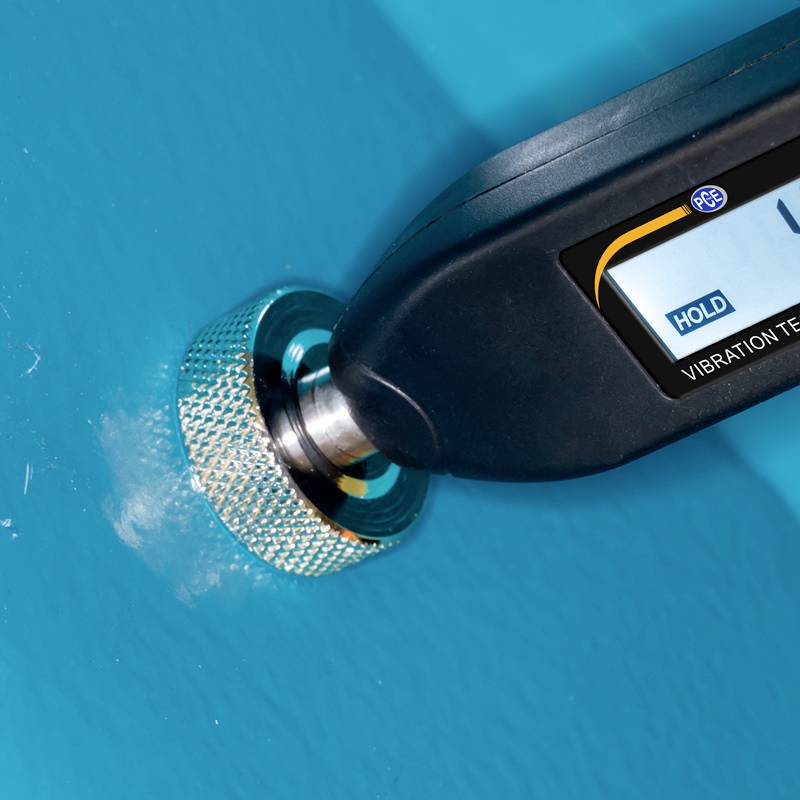 Een vibrometertoestel raakt een blauwe oppervlakte aan en toont een meetwaarde in het display.