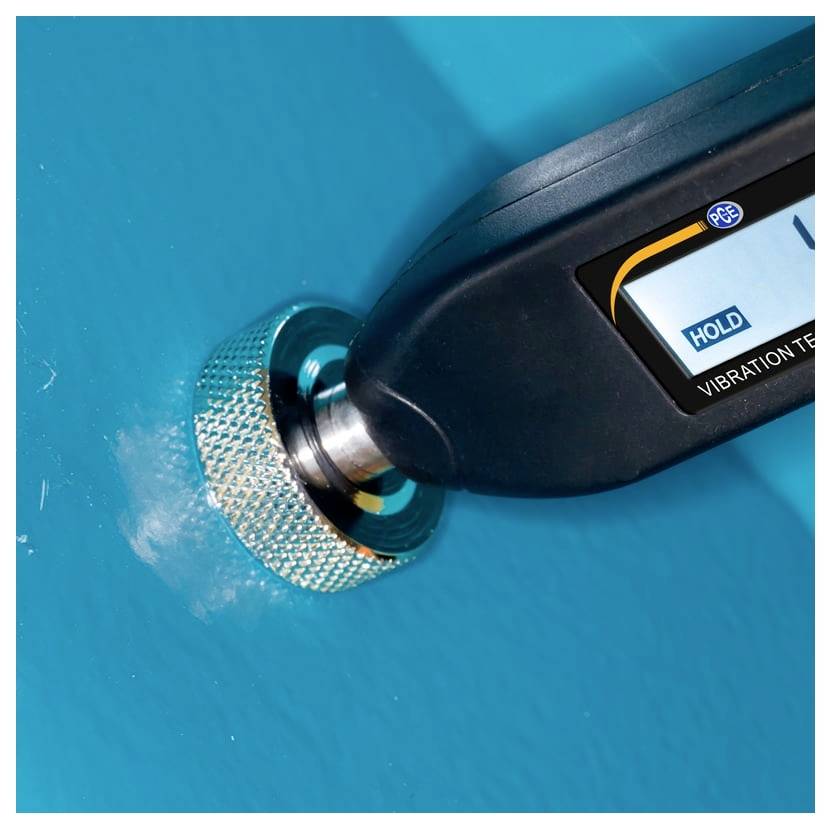 Digitale trillingmeter tegen een blauw oppervlak gedrukt, met 'HOLD' op het display.