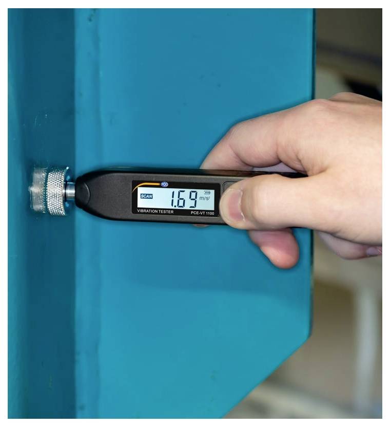 Handheld trillingstester die een blauw metalen oppervlak meet, met een waarde van 1,69 mm/s op het digitale display.